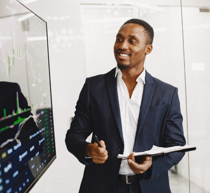 African man in a black suit. Big TV screen. Guy shows presentation.