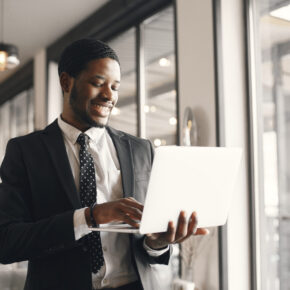 African man in a black suit. Guy with beard. Man with laptop.